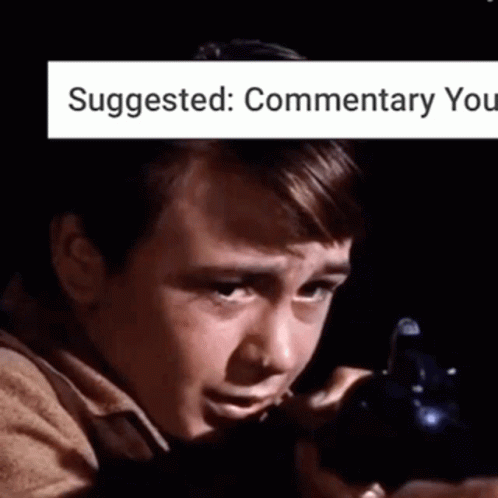 A Young Boy Is Holding A Gun In A Dark Room With The Words Suggested : Commentary You Above Him . GIF