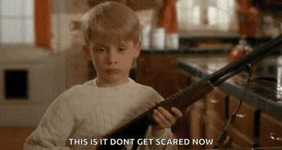 A Young Boy Is Holding A Shotgun In A Kitchen And Saying `` This Is It Do N't Get Scared Now '' . GIF