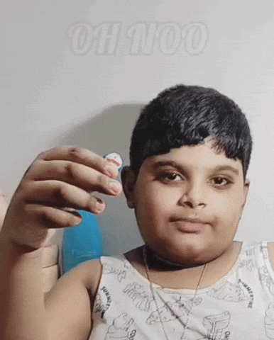 A Young Boy Is Holding Something In His Hand And The Word Oh Too Is Behind Him GIF