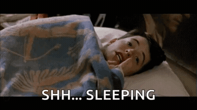 A Young Boy Is Laying In Bed Under A Blanket With The Words `` Shh ... Sleeping '' . GIF