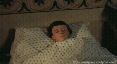A Young Boy Is Laying In Bed With His Eyes Closed GIF