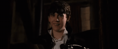 A Young Boy Is Laying On A Bed In The Dark . GIF