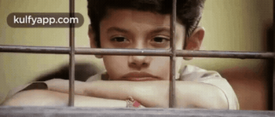 A Young Boy Is Looking Out Of A Window With His Head Resting On A Railing . GIF