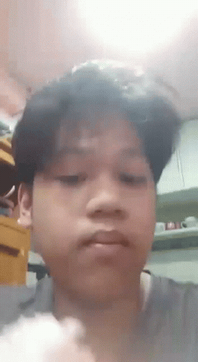 A Young Boy Is Making A Funny Face In A Kitchen While Holding A Piece Of Food . GIF