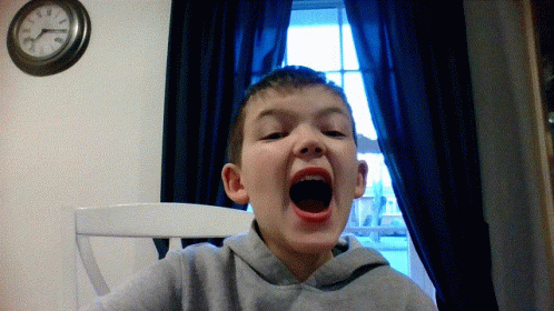 A Young Boy Is Making A Funny Face In Front Of A Clock That Shows The Time As Almost 5:00 GIF