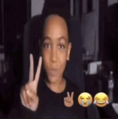 A Young Boy Is Making A Peace Sign In Front Of A Screen With Emojis . GIF