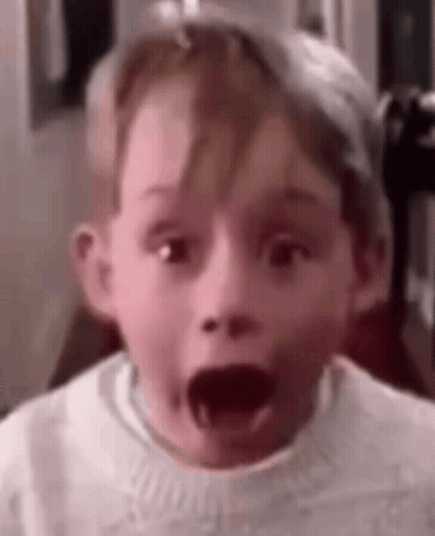 A Young Boy Is Making A Surprised Face With His Mouth Wide Open . GIF