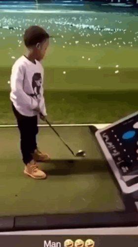 A Young Boy Is Playing Golf On A Driving Range GIF
