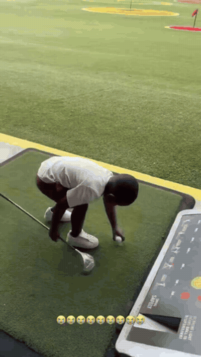 A Young Boy Is Playing Golf On A Driving Range . GIF