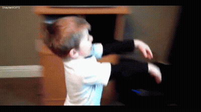 A Young Boy Is Playing With A Remote Control In Front Of A Tv .. GIF