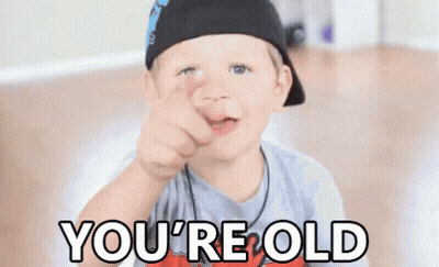 A Young Boy Is Pointing At The Camera With The Words `` You 'Re Old '' Written Below Him . GIF