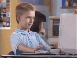 A Young Boy Is Sitting At A Desk In Front Of A Computer Monitor . GIF
