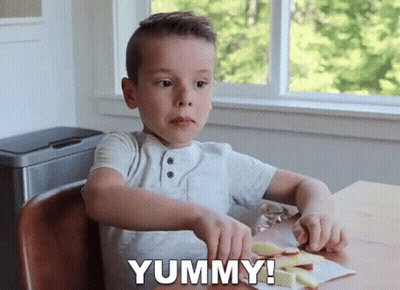 A Young Boy Is Sitting At A Table Cutting An Apple And Says Yummy ! GIF