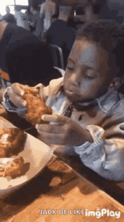 A Young Boy Is Sitting At A Table Eating Fried Chicken With A Fork . GIF