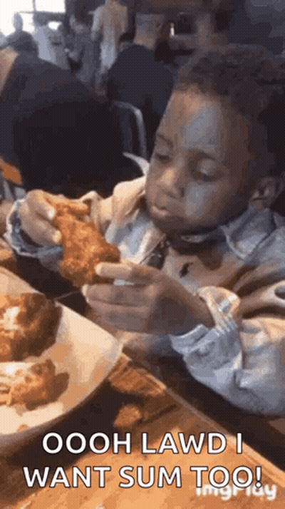 A Young Boy Is Sitting At A Table Eating Fried Chicken With A Fork . GIF