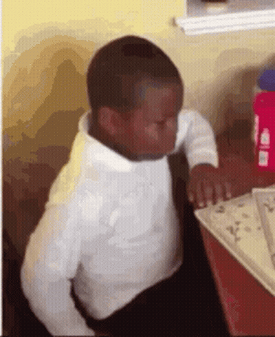 A Young Boy Is Sitting At A Table With A Book And A Bottle Of Water . GIF