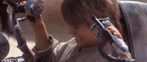 A Young Boy Is Sitting In A Chair And Holding A Toy Gun GIF