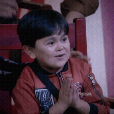A Young Boy Is Sitting In A Chair With His Hands Folded And The Words Pratiksha On The Bottom GIF