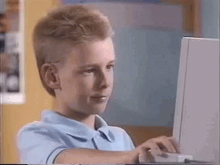 A Young Boy Is Sitting In Front Of A Laptop Computer . GIF