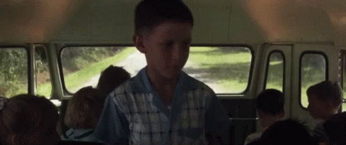 A Young Boy Is Sitting In The Back Of A School Bus GIF