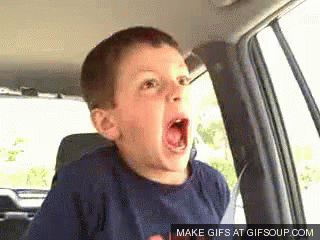 A Young Boy Is Sitting In The Back Seat Of A Car With His Mouth Wide Open . GIF