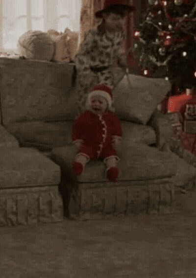 A Young Boy Is Sitting On A Couch Next To A Stuffed Monkey . GIF