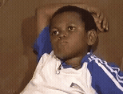 A Young Boy Is Sitting On A Couch With His Hands On His Head And Making A Funny Face . GIF