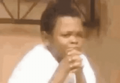 A Young Boy Is Sitting With His Hands Folded In Prayer . GIF