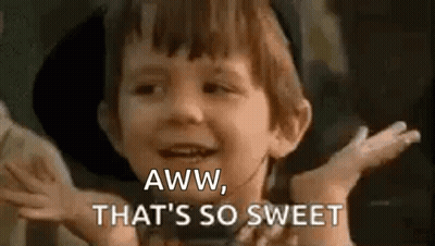A Young Boy Is Smiling And Saying `` Aww , That 'S So Sweet '' With His Hands Outstretched . GIF