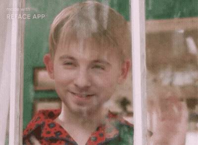 A Young Boy Is Smiling While Looking Out A Window . GIF