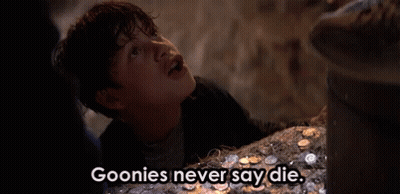 A Young Boy Is Standing In Front Of A Pile Of Coins And Says Goonies Never Say Die . GIF