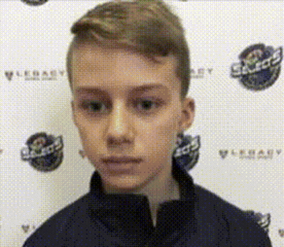 A Young Boy Is Standing In Front Of A Wall With Logos On It And Looking At The Camera . GIF