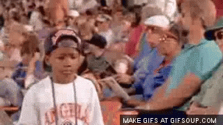 A Young Boy Is Standing In The Middle Of A Crowd Of People . GIF
