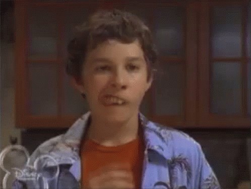 A Young Boy Is Sticking His Tongue Out While Wearing A Blue Shirt . GIF