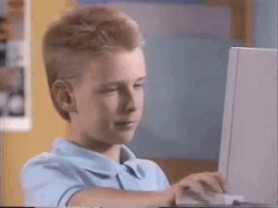 A Young Boy Is Using A Laptop Computer And Making A Funny Face . GIF