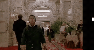 A Young Boy Is Walking Down A Hallway In A Hotel . GIF