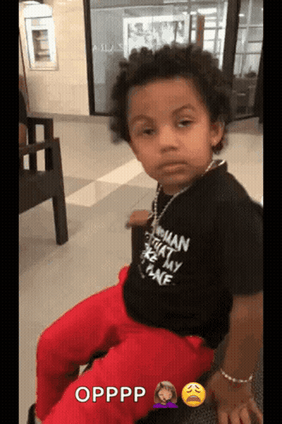 A Young Boy Is Wearing A Black Shirt That Says Opppp On It GIF