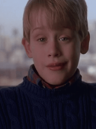 A Young Boy Is Wearing A Blue Sweater And A Plaid Shirt . GIF