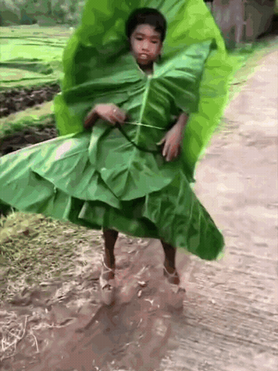 A Young Boy Is Wearing A Green Leaf Dress And High Heels GIF