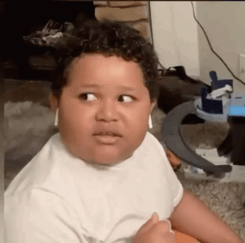 A Young Boy Is Wearing Headphones And Making A Funny Face While Sitting On The Floor . GIF