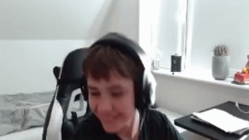 A Young Boy Is Wearing Headphones And Smiling While Sitting In A Chair . GIF