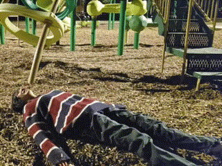 A Young Boy Laying On The Ground In A Playground GIF