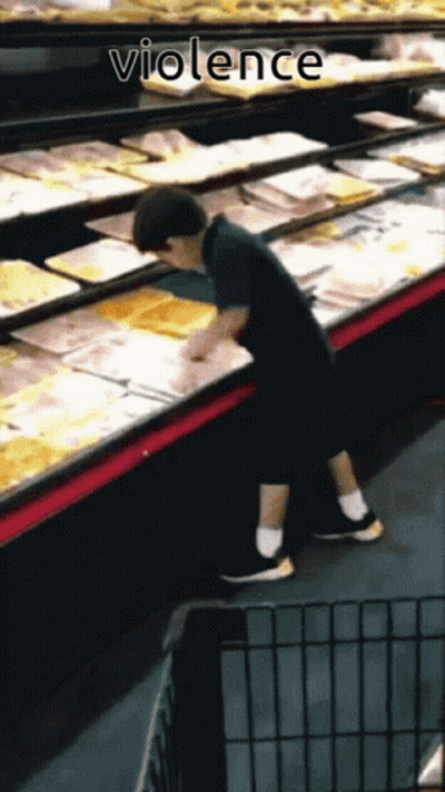 A Young Boy Reaches Into A Display Case In A Grocery Store With The Word Violence Below Him GIF