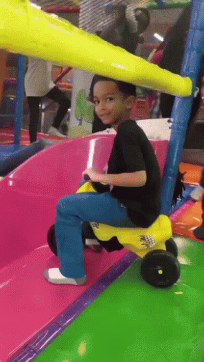 A Young Boy Riding A Yellow Toy Car On A Slide GIF