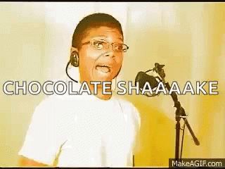 A Young Boy Singing Into A Microphone With The Words Chocolate Shaaaake Written Above Him GIF