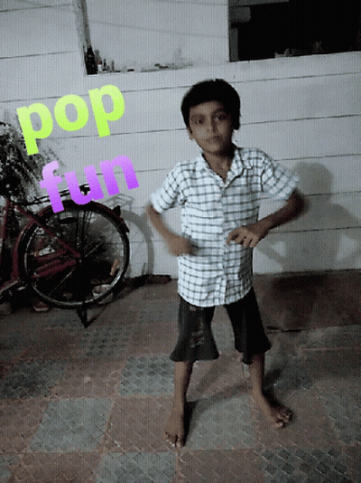 A Young Boy Stands In Front Of A Wall With The Words Pop And Fun Written On It GIF
