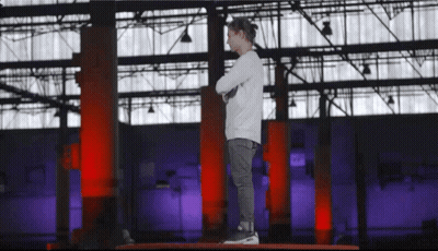 A Young Boy Stands On A Platform With His Arms Crossed In Front Of A Large Building GIF