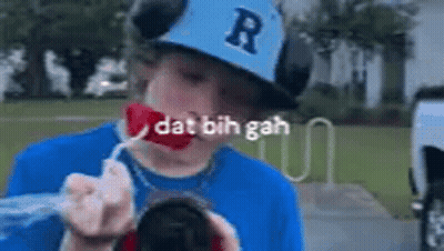 A Young Boy Wearing A Baseball Cap And A Blue Shirt Is Blowing Bubbles Out Of A Can . GIF