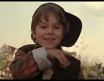 A Young Boy Wearing A Black Hat And A Plaid Shirt Is Smiling GIF