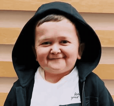A Young Boy Wearing A Black Hooded Jacket And A White Shirt That Says Feel Your GIF